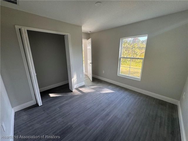 unfurnished bedroom with dark wood-type flooring and a closet