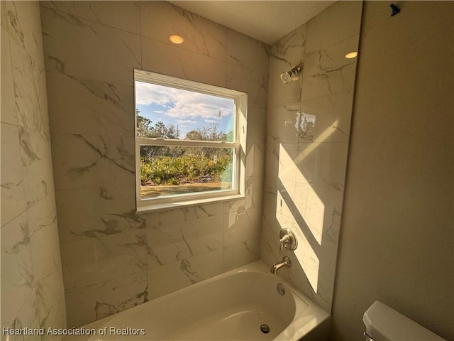 bathroom with tiled shower / bath and toilet