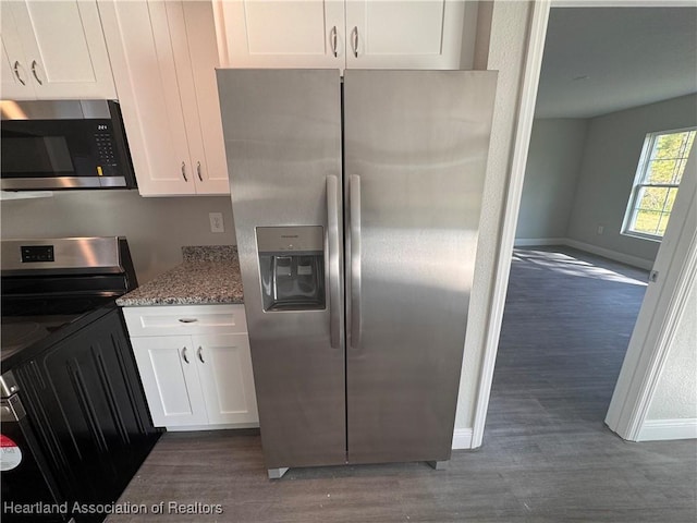 kitchen with dark wood-type flooring, appliances with stainless steel finishes, white cabinetry, light stone counters, and washer / clothes dryer