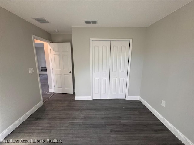 unfurnished bedroom featuring dark hardwood / wood-style floors and a closet