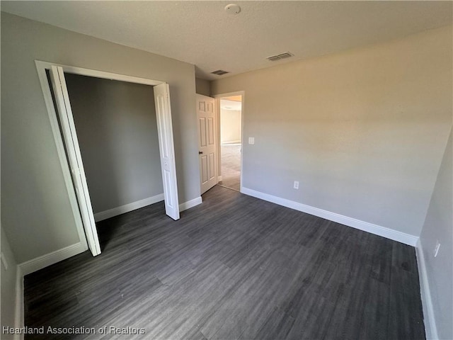 unfurnished bedroom with dark wood-type flooring and a closet