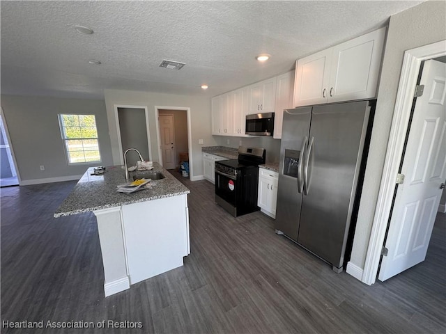 kitchen with dark hardwood / wood-style floors, sink, white cabinets, a kitchen island with sink, and stainless steel appliances