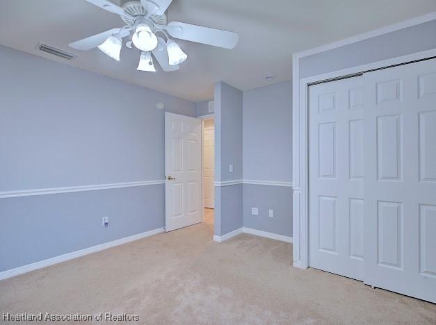 unfurnished bedroom with visible vents, baseboards, light carpet, a closet, and a ceiling fan