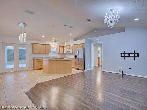 kitchen with a notable chandelier, stainless steel fridge with ice dispenser, light brown cabinets, and a center island