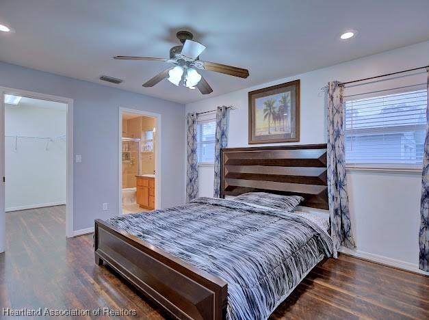 bedroom with visible vents, baseboards, wood finished floors, and a spacious closet