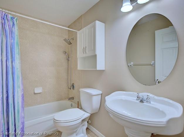 bathroom with toilet, shower / tub combo, and a sink