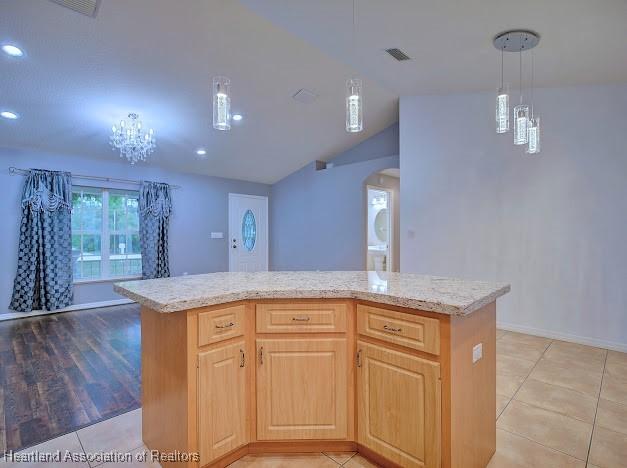 kitchen with visible vents, arched walkways, light tile patterned flooring, light stone countertops, and vaulted ceiling