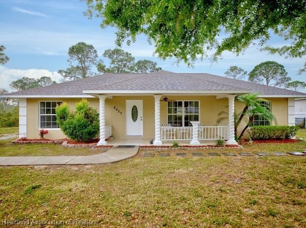 single story home featuring stucco siding, a porch, a front yard, and a shingled roof