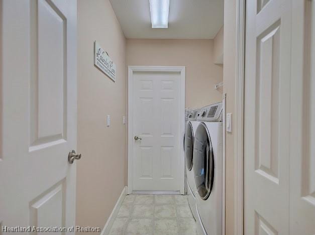 clothes washing area with laundry area, washing machine and dryer, and baseboards