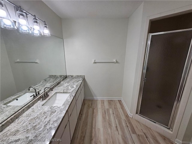 bathroom with hardwood / wood-style flooring, vanity, an enclosed shower, and a textured ceiling