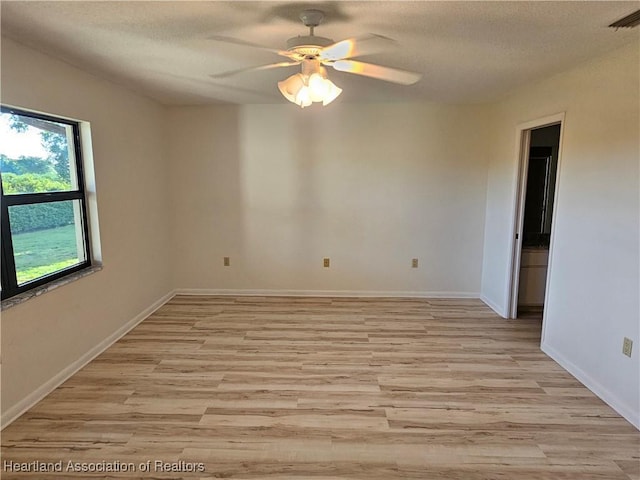 empty room featuring ceiling fan, light hardwood / wood-style flooring, and a textured ceiling