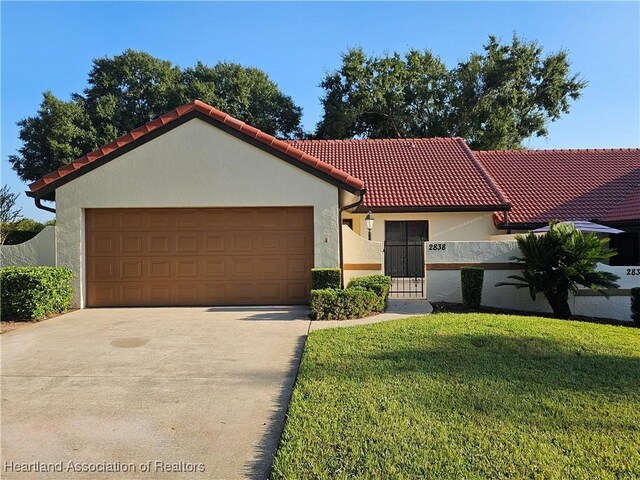 mediterranean / spanish-style home with a front yard and a garage