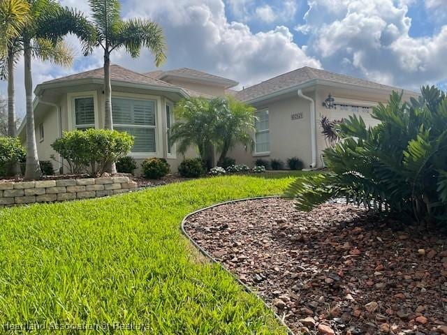 3929 Puma Dr, Avon Park, FL 33825 - view of front of property with a front lawn, an attached garage, and stucco siding