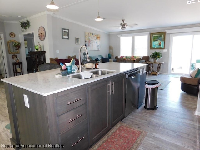 kitchen with sink, dishwasher, hanging light fixtures, ornamental molding, and a center island with sink