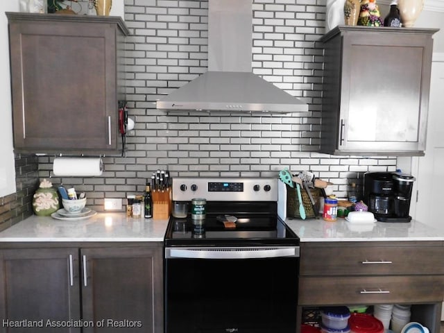 kitchen featuring dark brown cabinets, electric stove, decorative backsplash, and wall chimney exhaust hood