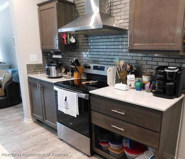 kitchen with stainless steel electric stove, backsplash, light hardwood / wood-style floors, dark brown cabinets, and wall chimney exhaust hood