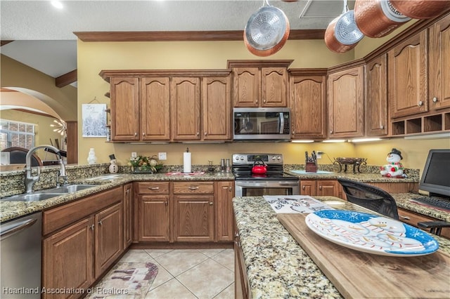 kitchen featuring sink, stainless steel appliances, light stone counters, lofted ceiling, and light tile patterned floors