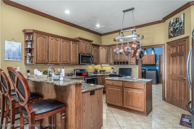 kitchen featuring kitchen peninsula, appliances with stainless steel finishes, a breakfast bar, a textured ceiling, and pendant lighting