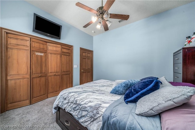 carpeted bedroom with vaulted ceiling, ceiling fan, and a textured ceiling