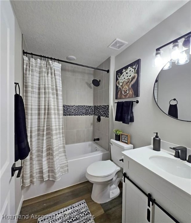 full bathroom featuring vanity, hardwood / wood-style flooring, toilet, shower / bathtub combination with curtain, and a textured ceiling