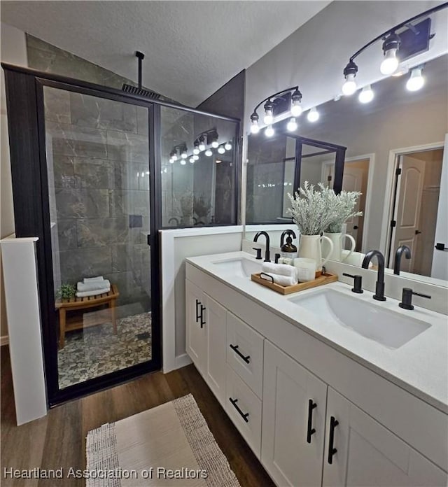 bathroom with wood-type flooring, a textured ceiling, vaulted ceiling, vanity, and a shower with shower door