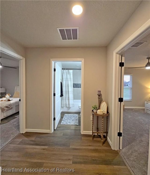 corridor featuring a textured ceiling and dark wood-type flooring