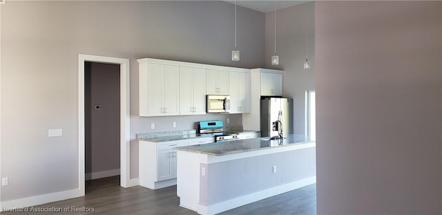 kitchen with decorative light fixtures, stainless steel appliances, white cabinetry, and light stone counters