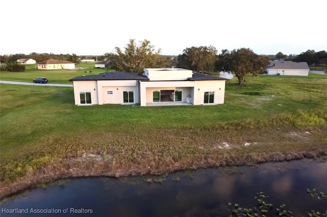 rear view of property with a water view and a yard