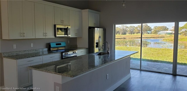 kitchen featuring sink, white cabinets, stone countertops, a water view, and appliances with stainless steel finishes