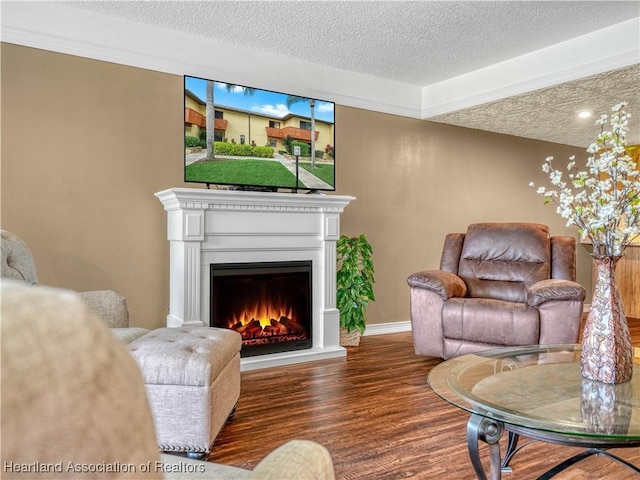 living area with a textured ceiling, a lit fireplace, wood finished floors, and baseboards