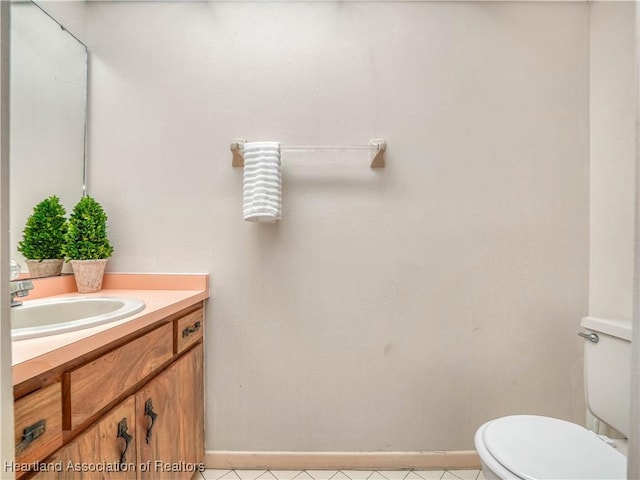 bathroom featuring toilet, vanity, and baseboards