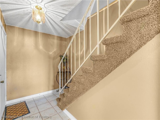 stairway with baseboards and tile patterned floors