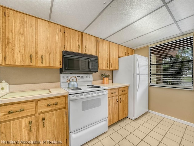 kitchen with light tile patterned floors, light countertops, white appliances, a drop ceiling, and baseboards