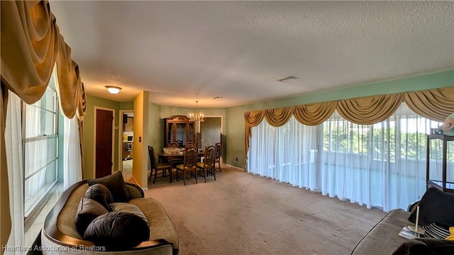 living room with carpet floors, a textured ceiling, and an inviting chandelier