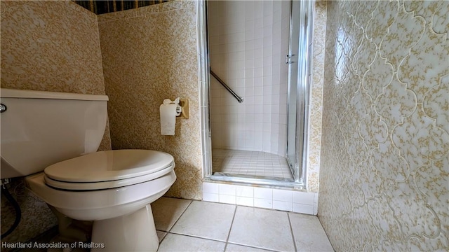 bathroom featuring tile patterned flooring, a shower with door, and toilet