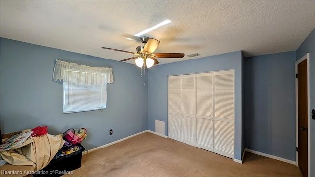 unfurnished bedroom with carpet flooring, ceiling fan, a closet, and a textured ceiling