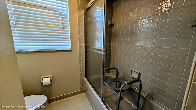 bathroom featuring tile patterned flooring, toilet, and bath / shower combo with glass door