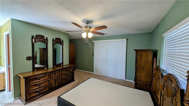 bedroom with a textured ceiling, light colored carpet, and ceiling fan