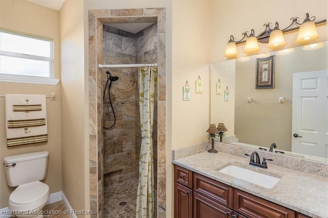 full bathroom with baseboards, tiled shower, toilet, and vanity