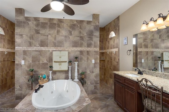 bathroom with vanity, tile walls, a tub with jets, and a walk in shower