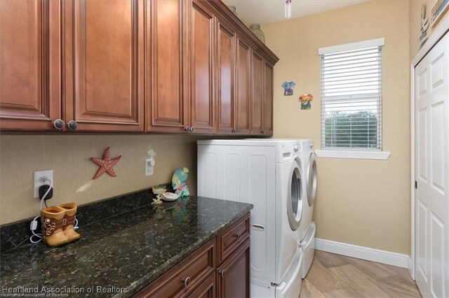 clothes washing area with cabinet space, light wood-style flooring, baseboards, and separate washer and dryer