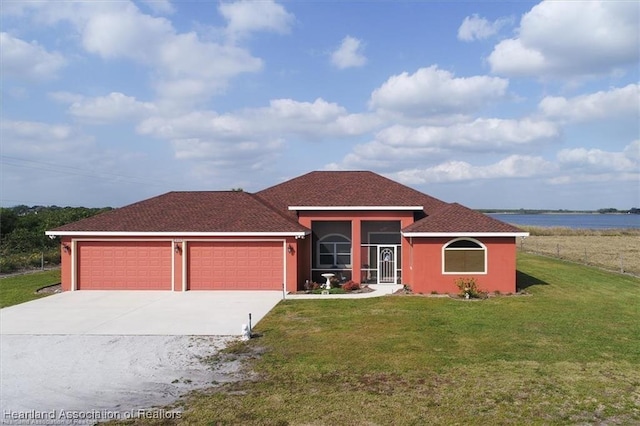 view of front facade featuring stucco siding, a water view, a front lawn, concrete driveway, and an attached garage