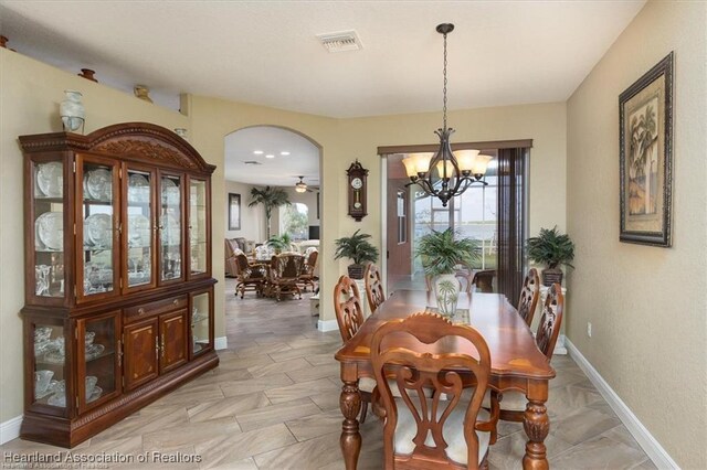 dining room featuring visible vents, arched walkways, plenty of natural light, and baseboards