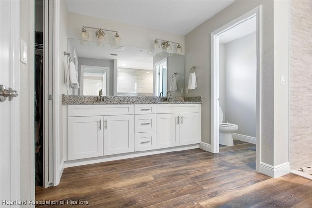 bathroom featuring hardwood / wood-style flooring, vanity, toilet, and a shower