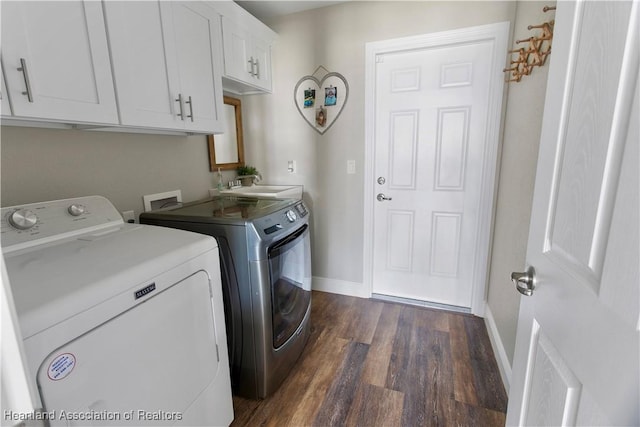 laundry room featuring sink, dark wood-type flooring, washing machine and dryer, and cabinets