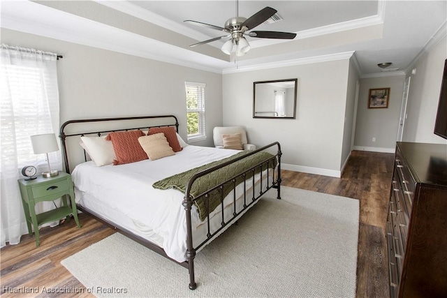 bedroom with a raised ceiling, crown molding, dark hardwood / wood-style floors, and ceiling fan