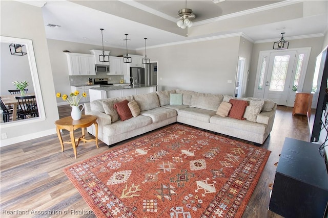 living room featuring hardwood / wood-style floors, ornamental molding, and ceiling fan