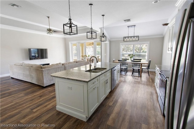 kitchen featuring appliances with stainless steel finishes, an island with sink, sink, ceiling fan, and light stone countertops