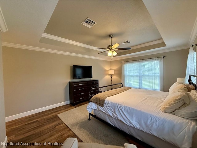 bedroom with dark wood-style floors, a raised ceiling, visible vents, and baseboards