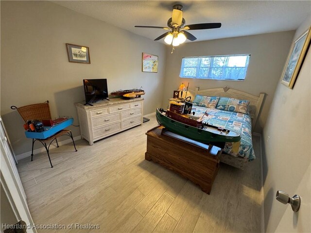 bedroom with light wood-style floors, ceiling fan, and baseboards